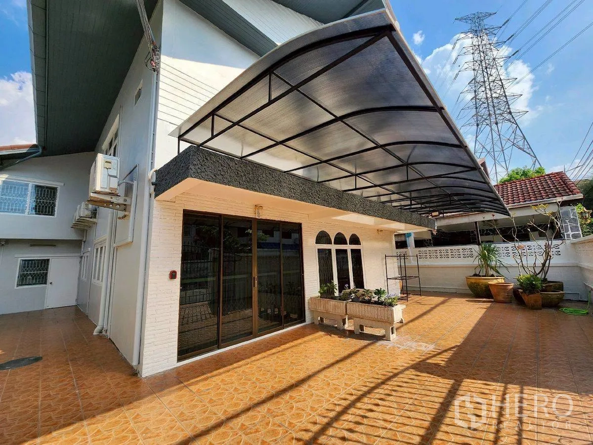 บ้านเดี่ยว for rent in Huai Khwang, Bangkok - ลานหน้าบ้านมีกันสาดกว้าง ประตูกระจกบานเลื่อน และกระบะต้นไม้