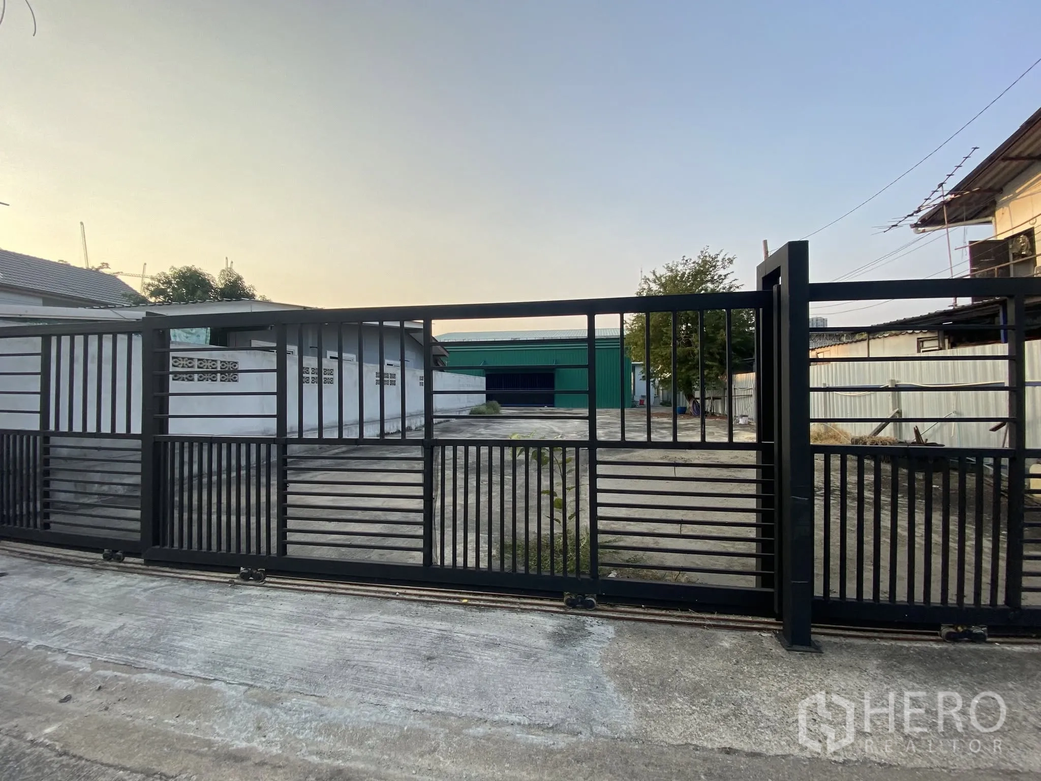 Warehouse for rent in Bang Na, Bangkok - Secure sliding front gate opening to the paved warehouse compound.