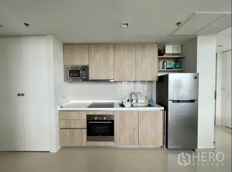 公寓 出售在Ratchathewi, Bangkok - 浅木色一字形厨房，配烤箱、电磁炉、微波炉和冰箱。