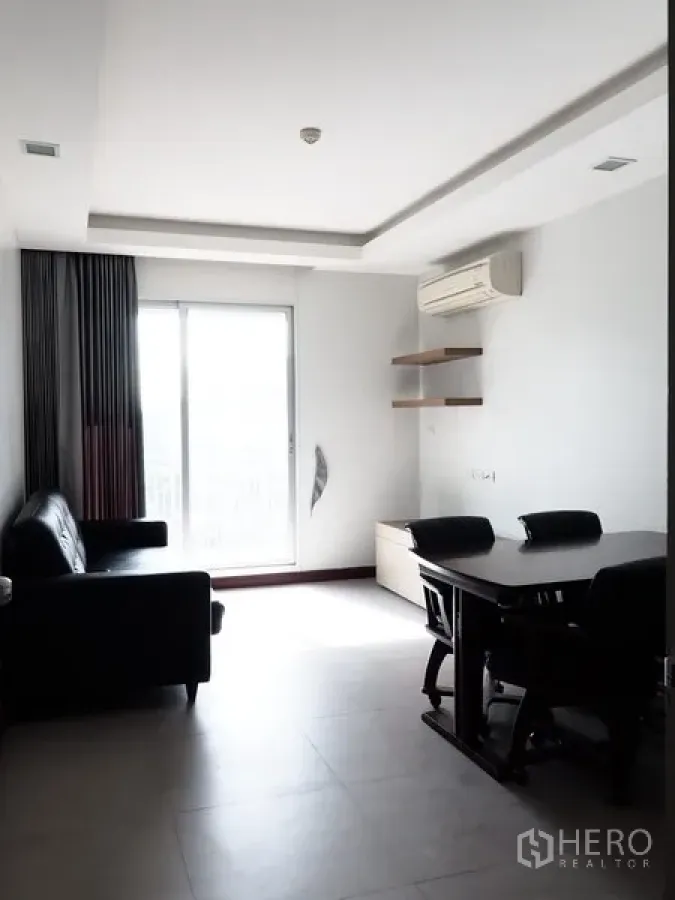 公寓 出租在Huai Khwang, Bangkok - 明亮的客餐厅，落地推拉门通向阳台，黑色沙发、餐桌和壁挂空调