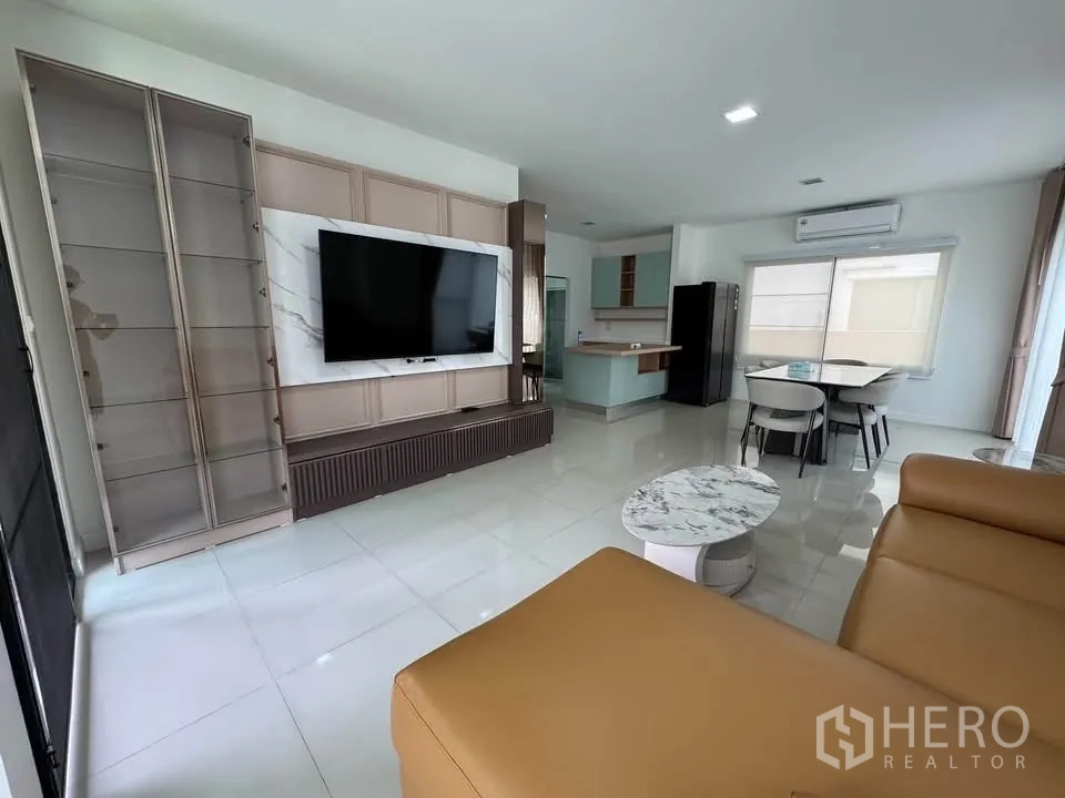 บ้านเดี่ยว for rent in Prawet, Bangkok - ห้องนั่งเล่นสว่างติดทีวีผนัง ตู้โชว์ โซฟาหนัง และโต๊ะกลางลายหินอ่อน