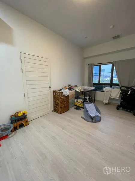 Condominium for sale in Sathon, Bangkok - Bright spare bedroom with light wood floors, a city-view window and storage units.