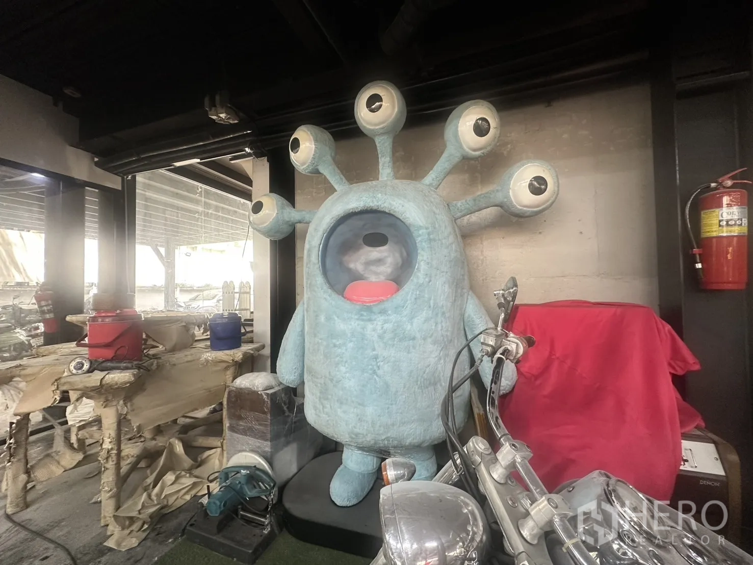 Retail Space for rent in Watthana, Bangkok - Interior display area with a large sculptural figure, motorcycle, and fire extinguisher by glass walls.