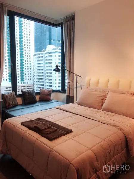 คอนโด ให้เช่าในWatthana, Bangkok - ห้องนอนอบอุ่น เตียงหัวบุผ้า ม้านั่งริมหน้าต่าง และกระจกมุมขนาดใหญ่ชมวิวสกายไลน์กรุงเทพฯ