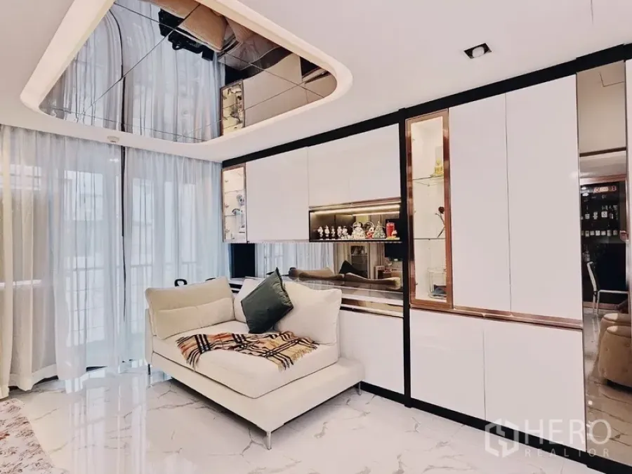 Condominium for sale in Bang Rak, Bangkok - Bright Silom condo living room with mirrored ceiling, white built-ins, sheer curtains and marble floor.