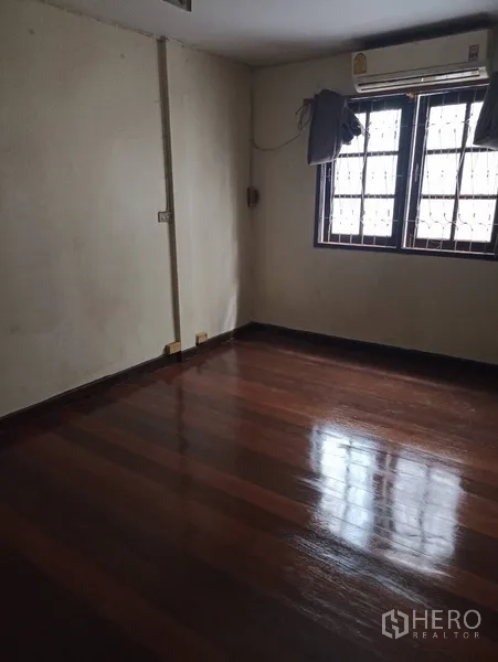 联排别墅 出租或出售在Wang Thonglang, Bangkok - 卧室配深色亮木地板、窗户防护栏和空调。