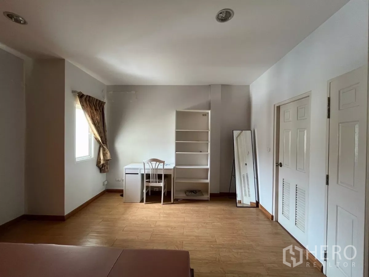 Townhouse for rent in Bang Kho Laem, Bangkok - Same bedroom with study desk, shelving unit, and standing mirror by windows.