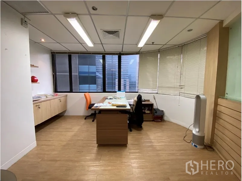 办公空间 出租在Khlong Toei, Bangkok - 转角主管办公室，带全景窗、百叶与木地板，可见城市景观。