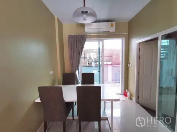 联排别墅 出租在Wang Thonglang, Bangkok - 餐厅配四把椅子、吊灯与空调，推拉玻璃门通往小阳台。