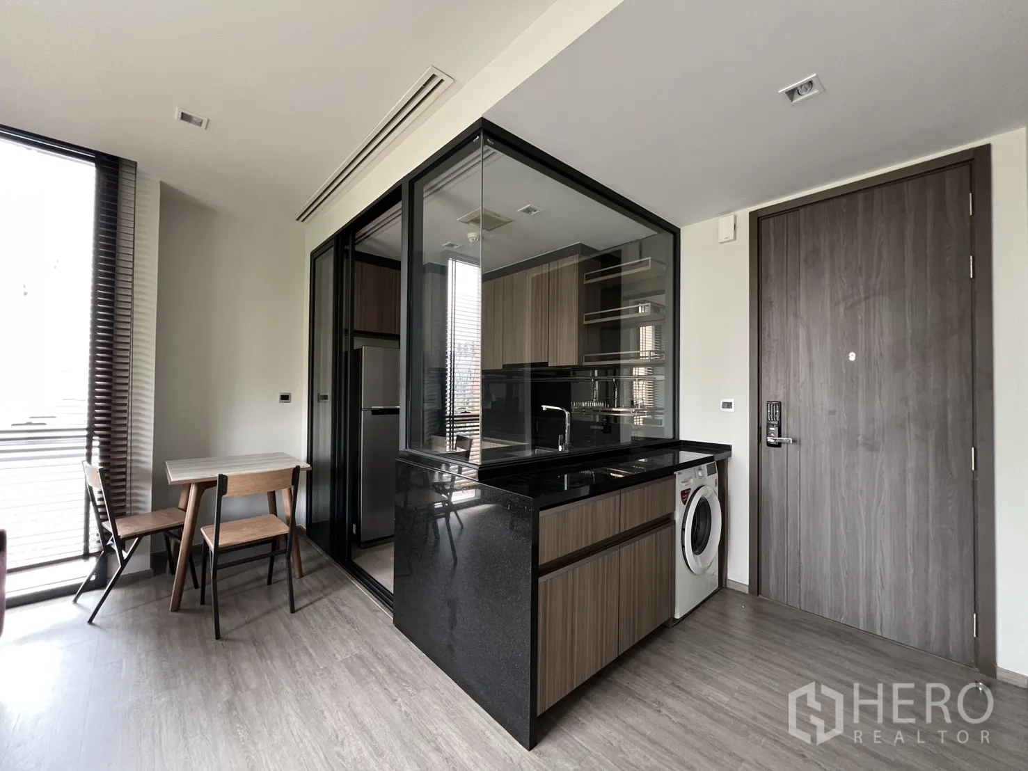 Condominium for rent in Watthana, Bangkok - Entry area with a dining nook and a glass-enclosed kitchen with a washer under the counter.