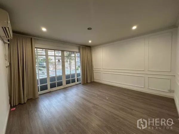 ทาวน์เฮาส์ ให้เช่าในWatthana, Bangkok - ห้องนั่งเล่นสว่างพื้นไม้ บัวผนัง และประตูกระจกบานเลื่อนพร้อมผ้าม่าน