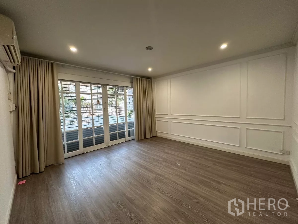 ทาวน์เฮาส์ ให้เช่าในWatthana, Bangkok - ห้องนั่งเล่นสว่างพื้นไม้ บัวผนัง และประตูกระจกบานเลื่อนพร้อมผ้าม่าน