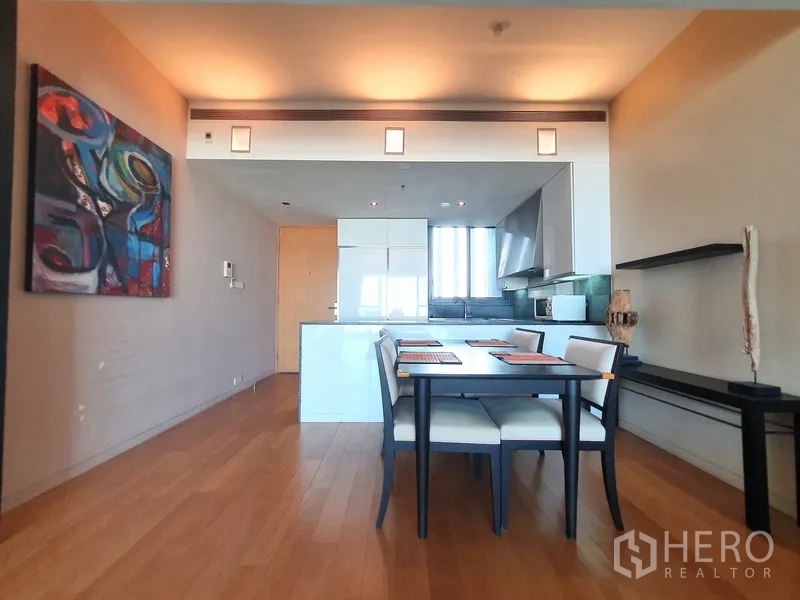 Condominium for rent in Sathon, Bangkok - Dining zone facing a modern open kitchen with glossy cabinetry and artwork.