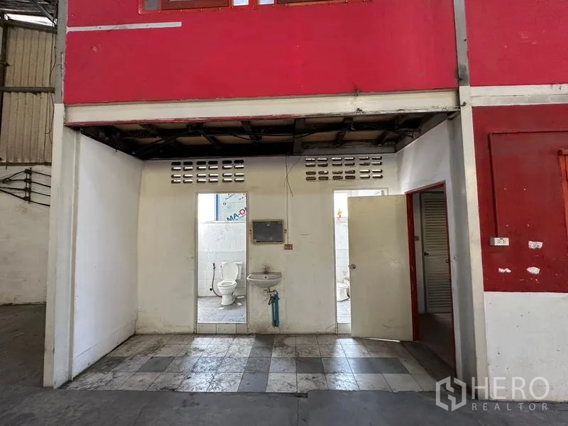 Warehouse for rent in Suan Luang, Bangkok - Warehouse restroom zone with two toilet stalls, a sink and tiled flooring under the office.