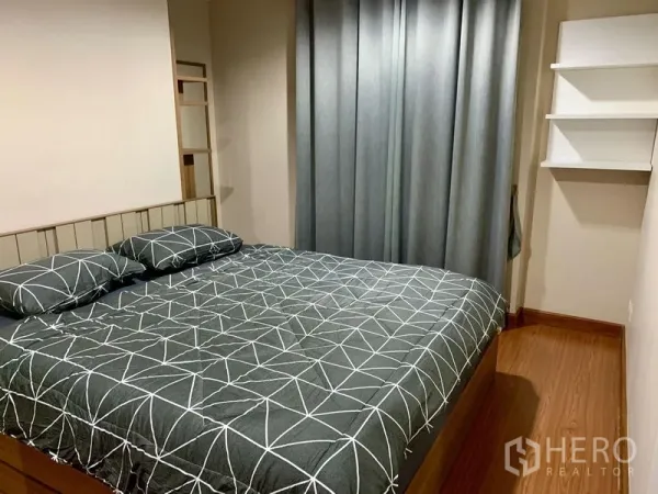 Condominium for rent in Huai Khwang, Bangkok - Cozy bedroom with double bed, grey curtains and floating shelves on warm wood flooring.