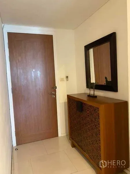 Condominium for rent in Watthana, Bangkok - Entry hallway featuring a wooden door, console cabinet, and wall-mounted mirror.