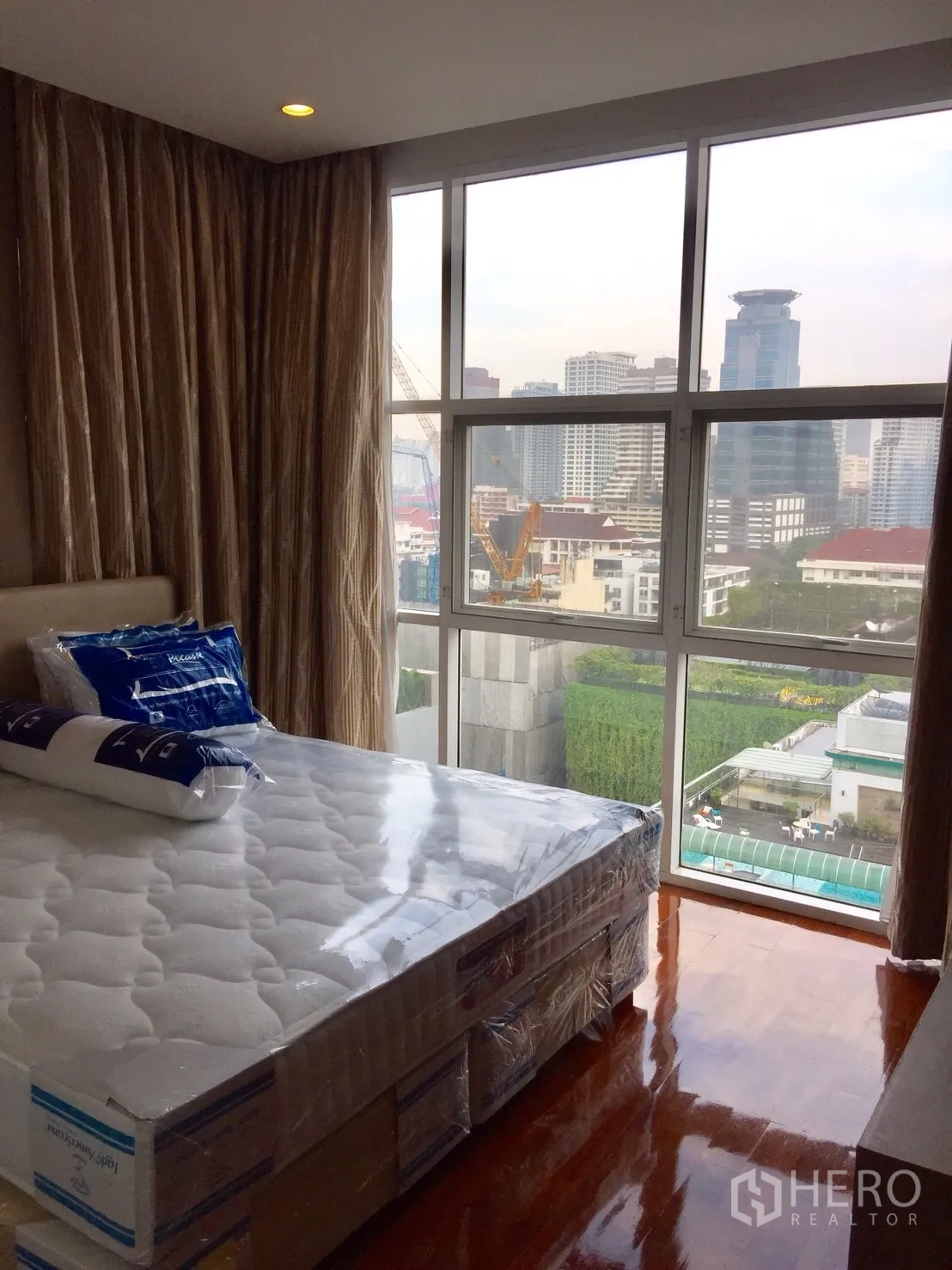Condominium for rent in Watthana, Bangkok - Bedroom with large windows, polished wood floor, new bed and outlook over the pool and landscaped garden.