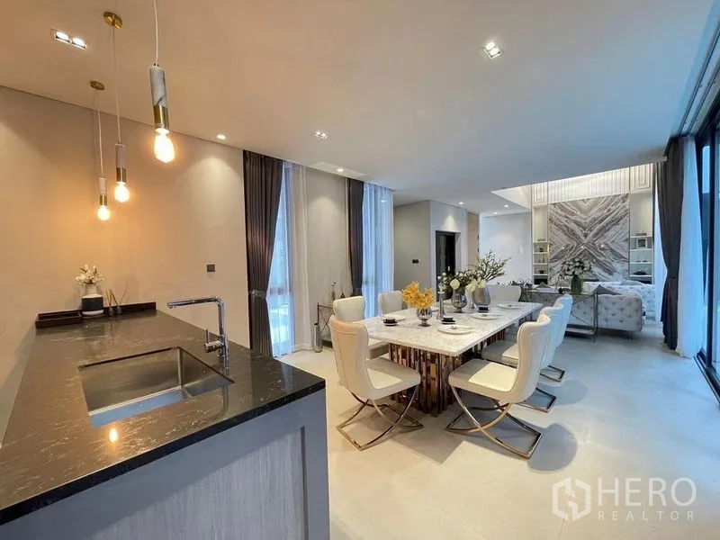 Detached House for sale in Suan Luang, Bangkok - Contemporary kitchen with a dark stone island, pendant lighting and open plan to the dining room.