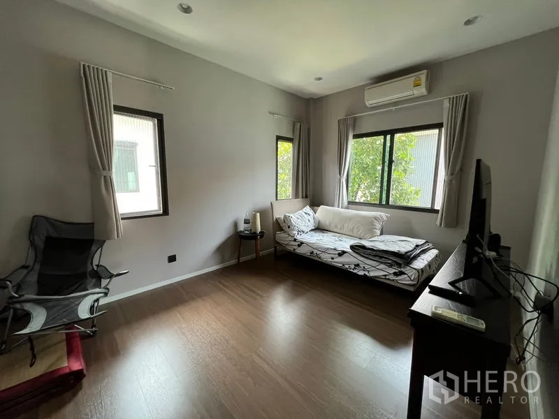 Detached House for sale in Bang Kapi, Bangkok - Light-filled bedroom with windows on two sides and wood floors.