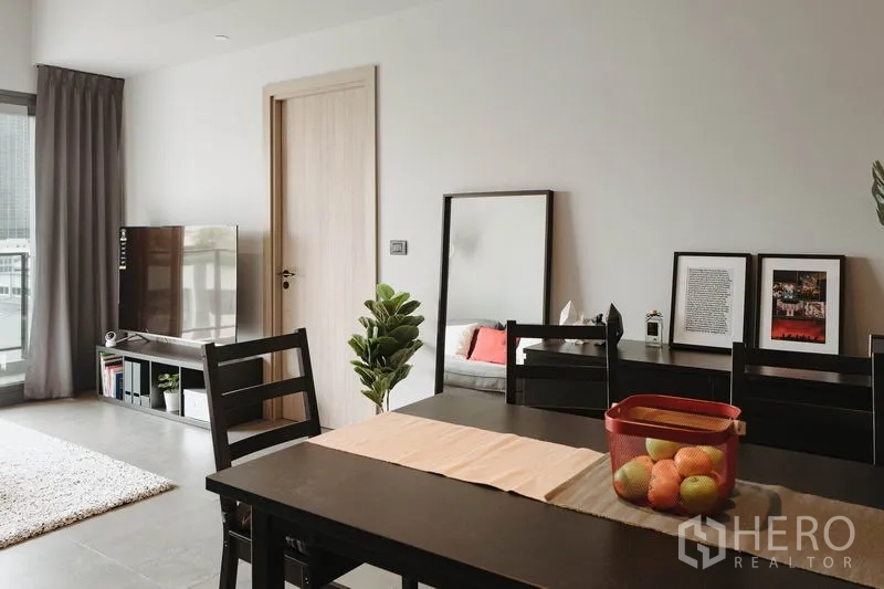 Condominium for rent in Watthana, Bangkok - Four-seat dining table near TV console and wall mirror in an airy living space.