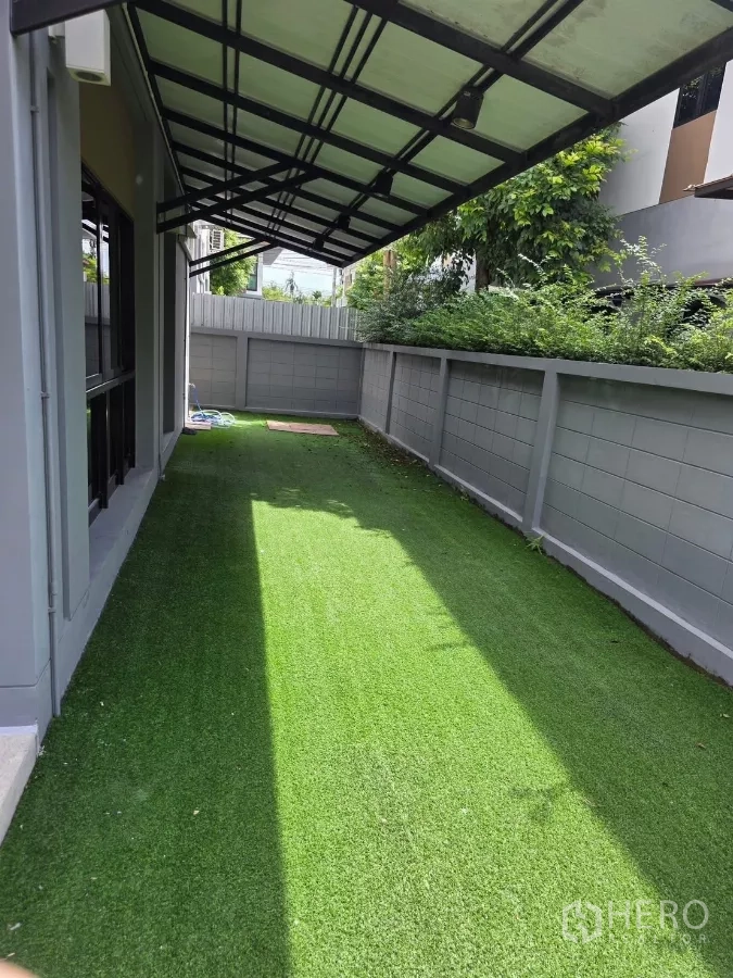Detached House for rent in Prawet, Bangkok - Side garden with artificial turf under a covered walkway beside the house.