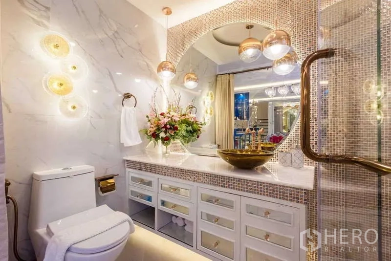 联排别墅 出租在Lat Phrao, Bangkok - 豪华浴室，大理石墙面、拱形镜与吊灯，金色台上盆。