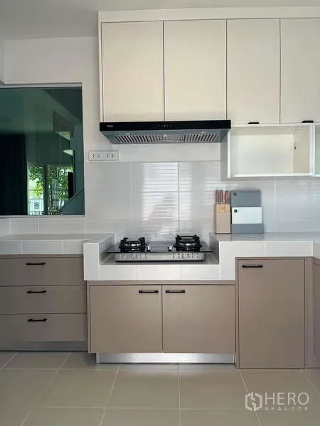 Detached House for rent in Bang Phli, Samut Prakan - Modern kitchen with gas hob, hood and upper and lower cabinets.