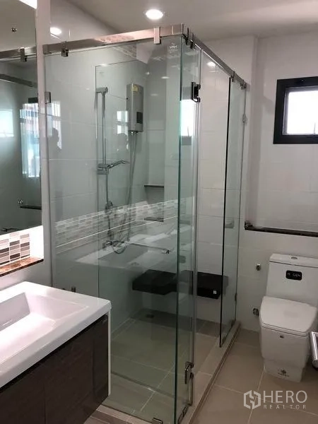 Detached House for rent in Bang Kapi, Bangkok - Contemporary bathroom with glass-enclosed shower, vanity and toilet.