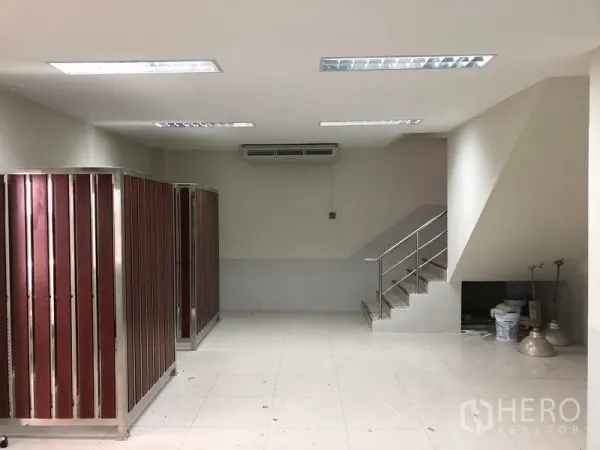 Factory for rent in Samut Prakan - Office lobby with tiled floor, stairway to a mezzanine and partitioned storage cabinets.