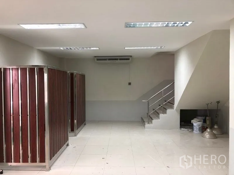 Factory for rent in Samut Prakan - Office lobby with tiled floor, stairway to a mezzanine and partitioned storage cabinets.