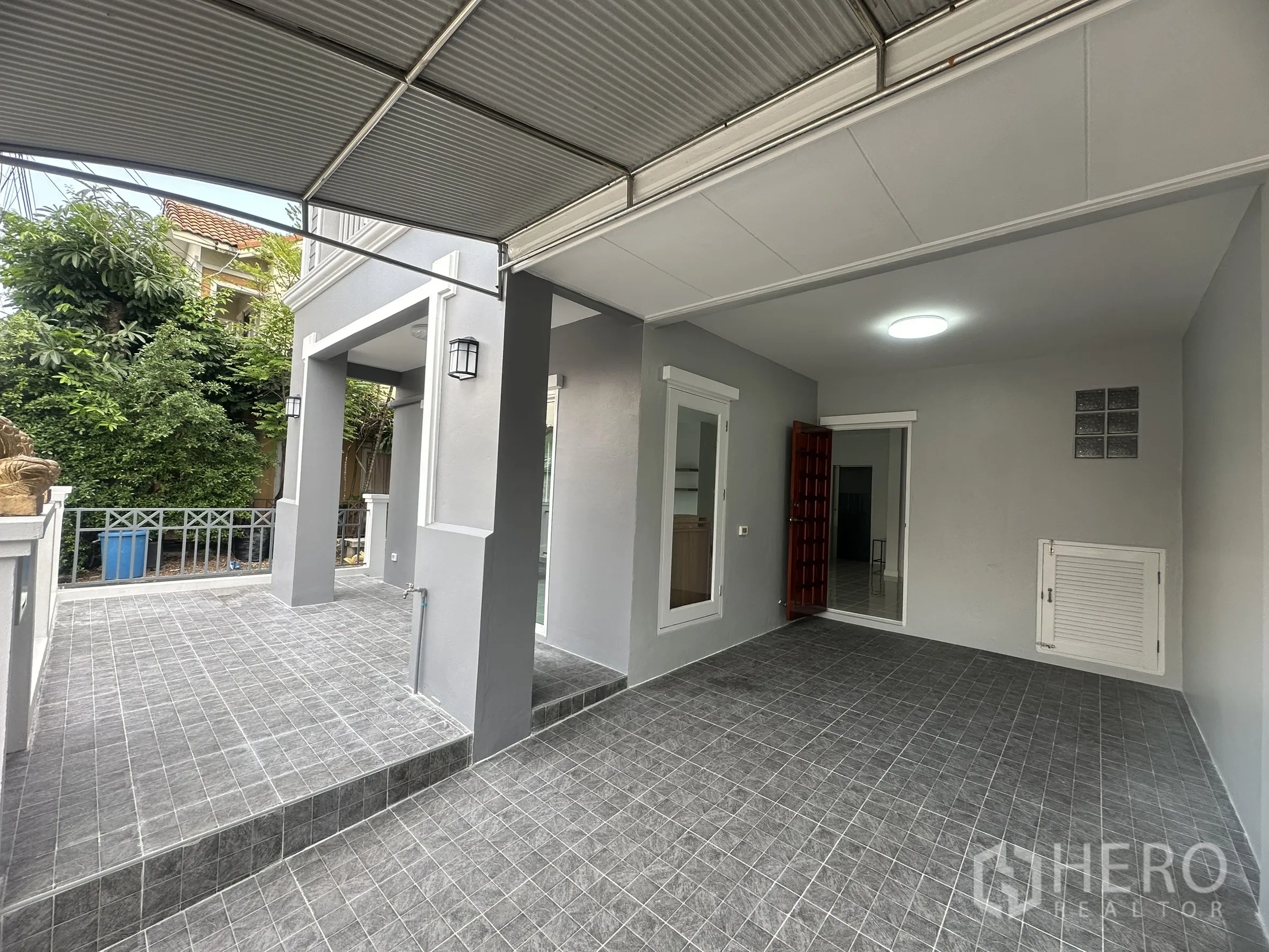 ทาวน์เฮาส์ ขายในLam Luk Ka, Pathum Thani - โรงจอดรถมีหลังคาและชานหน้าบ้านปูกระเบื้องสีเทา