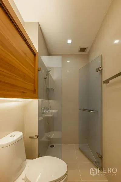 คอนโด ขายในWatthana, Bangkok - ห้องน้ำสไตล์โมเดิร์นพร้อมตู้กระจกอาบน้ำ สุขภัณฑ์ และไฟสว่างอบอุ่น โทนสีเบจ