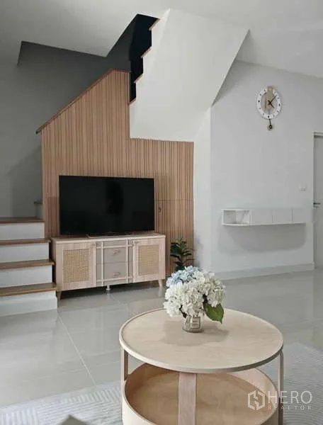 ทาวน์เฮาส์ ให้เช่าในBang Phli, Samut Prakan - ห้องนั่งเล่นสว่าง โทรทัศน์บนตู้บิวท์อินใต้บันได โต๊ะกลางทรงกลม และนาฬิกาแขวน