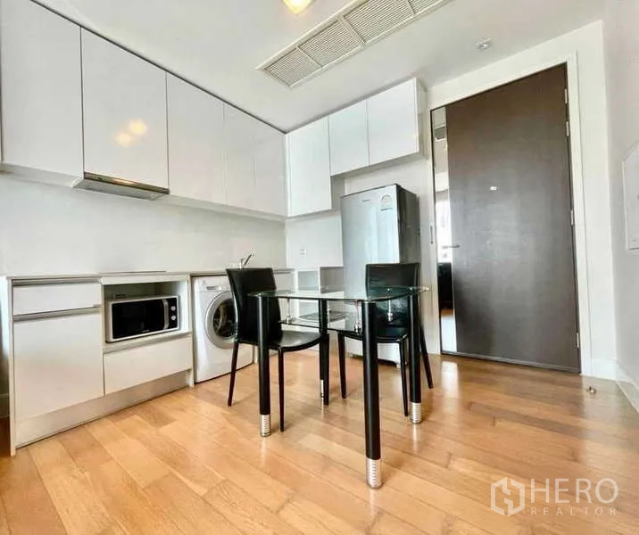 Condominium for rent in Bangkok - Dining nook for two beside full-height cabinetry and stainless fridge.