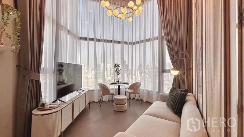 Condominium for rent - Corner living area with floor-to-ceiling curtains, sofa, TV console and expansive city view.