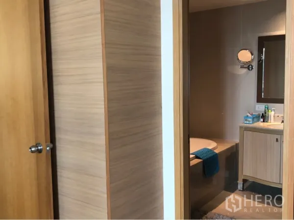 公寓 出租或出售在Sathon, Bangkok - 主卫配嵌入式浴缸、洗手台与墙面镜柜，木色装饰。