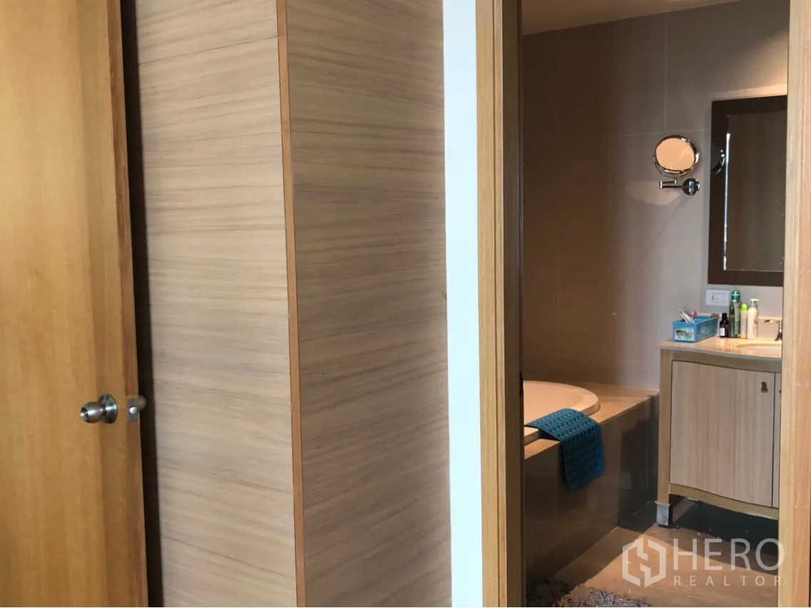 公寓 出租或出售在Sathon, Bangkok - 主卫配嵌入式浴缸、洗手台与墙面镜柜，木色装饰。