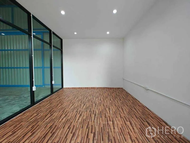 Warehouse for rent in Sam Phran, Nakhon Pathom - Bright office room with floor-to-ceiling glass partition and wood-pattern vinyl flooring.