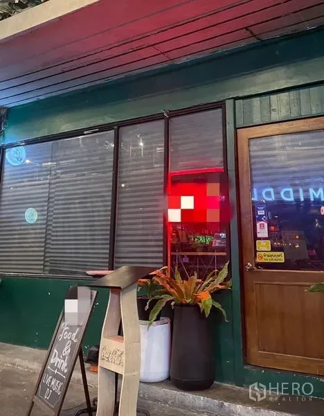 零售空间 出租 - 临街店面，绿色外立面，大面积玻璃与百叶窗、木门、黑板菜单与花盆。