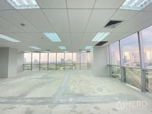 办公空间 出租在Chatuchak, Bangkok - 开放式办公楼层，吊顶灯具，两面玻璃呈现全景城市视野。