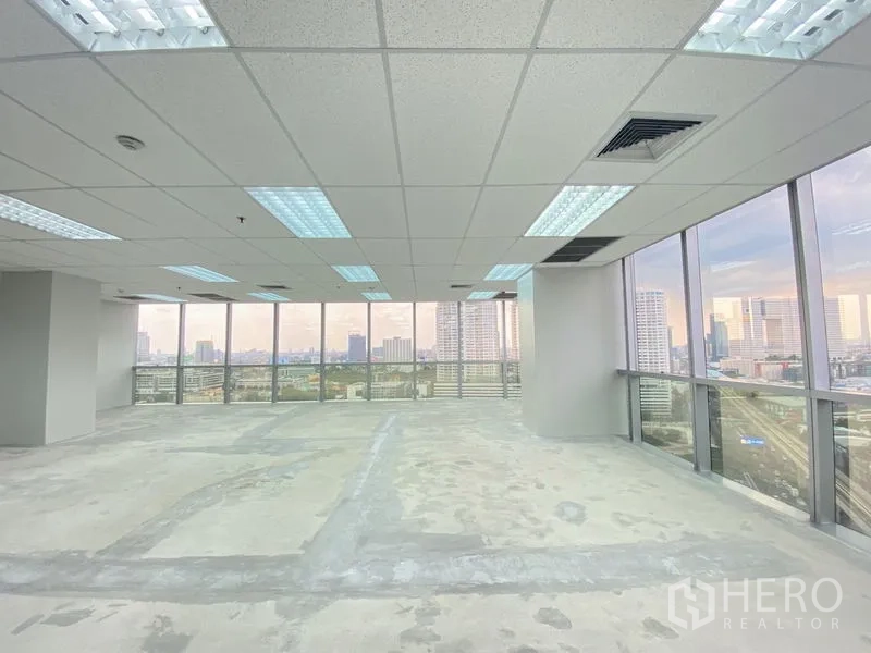 办公空间 出租在Chatuchak, Bangkok - 开放式办公楼层，吊顶灯具，两面玻璃呈现全景城市视野。