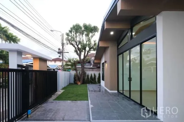 独立式住宅 出售在Bueng Kum, Bangkok - 前庭露台和草坪，落地推拉玻璃门，临街黑色金属围栏