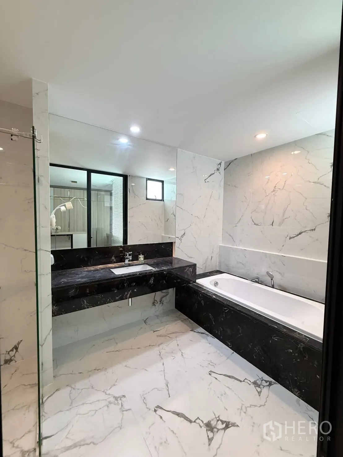 Townhouse for rent in Saphan Sung, Bangkok - Bathroom with marble tiles, black vanity and built-in bathtub.