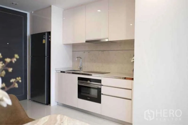 Condominium for rent in Sathon, Bangkok - Modern kitchenette with built-in oven, glossy cabinets and full-size fridge.