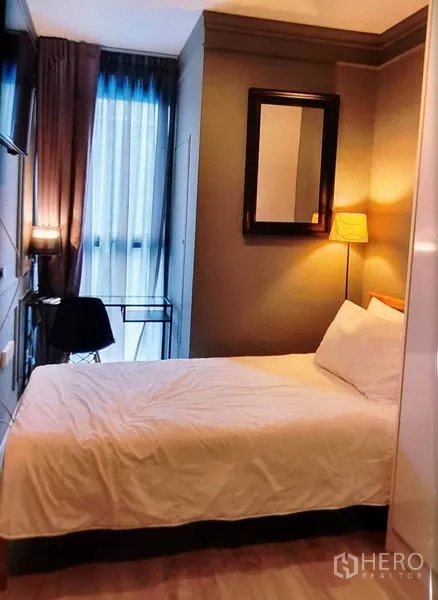 Condominium for rent in Phra Khanong, Bangkok - Bedroom with double bed, work desk by the window and warm lighting.