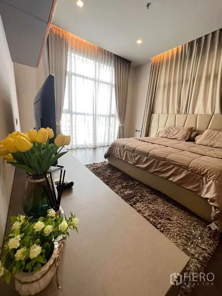 คอนโด ให้เช่าหรือขายในWatthana, Bangkok - ห้องนอนใหญ่ แสงอบอุ่น หน้าต่างบานใหญ่ ชุดเครื่องนอนสีเบจ และพรมหนานุ่ม