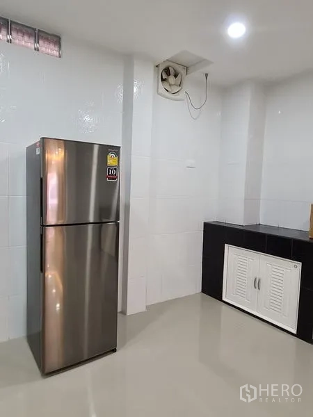 ทาวน์เฮาส์ ให้เช่าในKhlong Toei, Bangkok - มุมครัวมีตู้เย็นสแตนเลส พัดลมดูดอากาศ และผนังกระเบื้องสีขาว