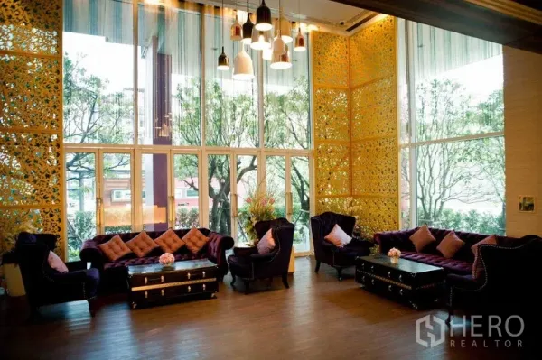 Condominium for rent in Watthana, Bangkok - Elegant high-ceiling lobby lounge with velvet sofas, large windows, pendant lights and golden decorative panels