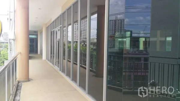 办公空间 出租在Phra Khanong, Bangkok - 沿阳台步道的玻璃立面办公室外景，映射城市天际线。