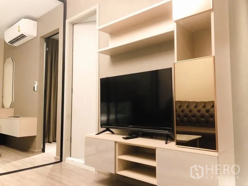 Condominium for rent in Watthana, Bangkok - Media wall with TV, shelving and mirror opposite the bedroom.